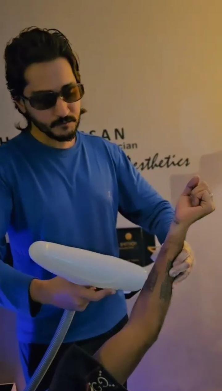 Practitioner performing laser tattoo removal on a client's arm
